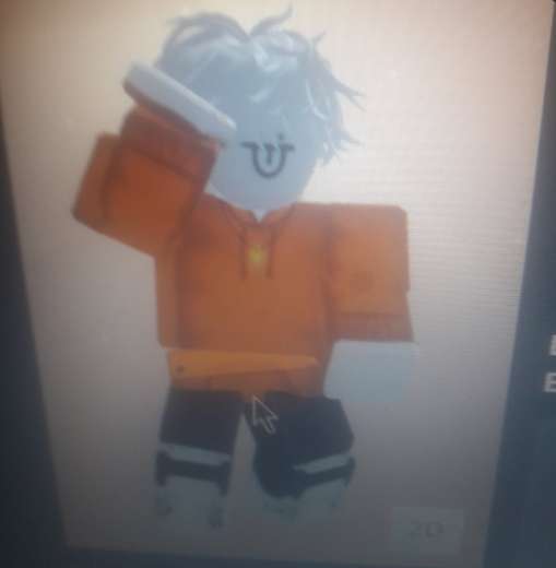 LayRo / Shans con pelo claro, sudadera naranja y pantalones oscuros.